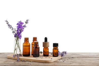 Photo of Bottles of essential oils and different plants on wooden table against white background