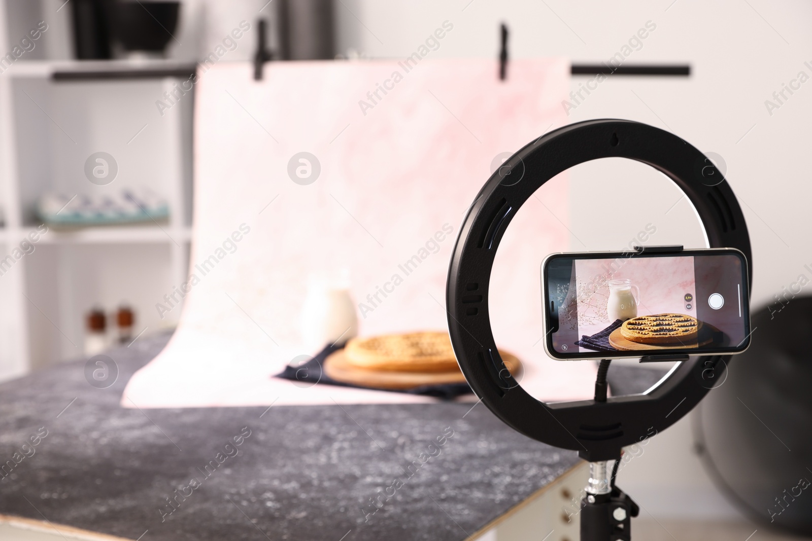 Photo of Shooting tasty pie and milk with smartphone in studio, selective focus. Professional food photography