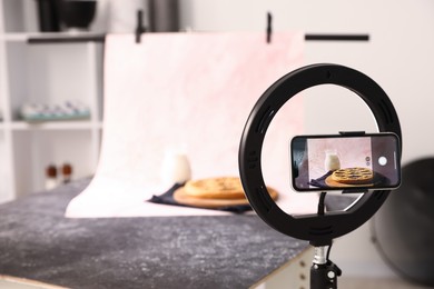 Photo of Shooting tasty pie and milk with smartphone in studio, selective focus. Professional food photography