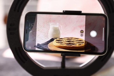 Photo of Shooting tasty pie and milk with smartphone in studio, selective focus. Professional food photography