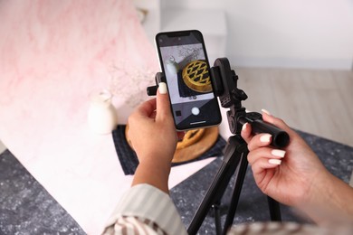 Photo of Woman taking picture of tasty pie and milk in studio, above view. Professional food photography