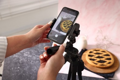 Photo of Woman taking picture of tasty pie and milk in studio, selective focus. Professional food photography
