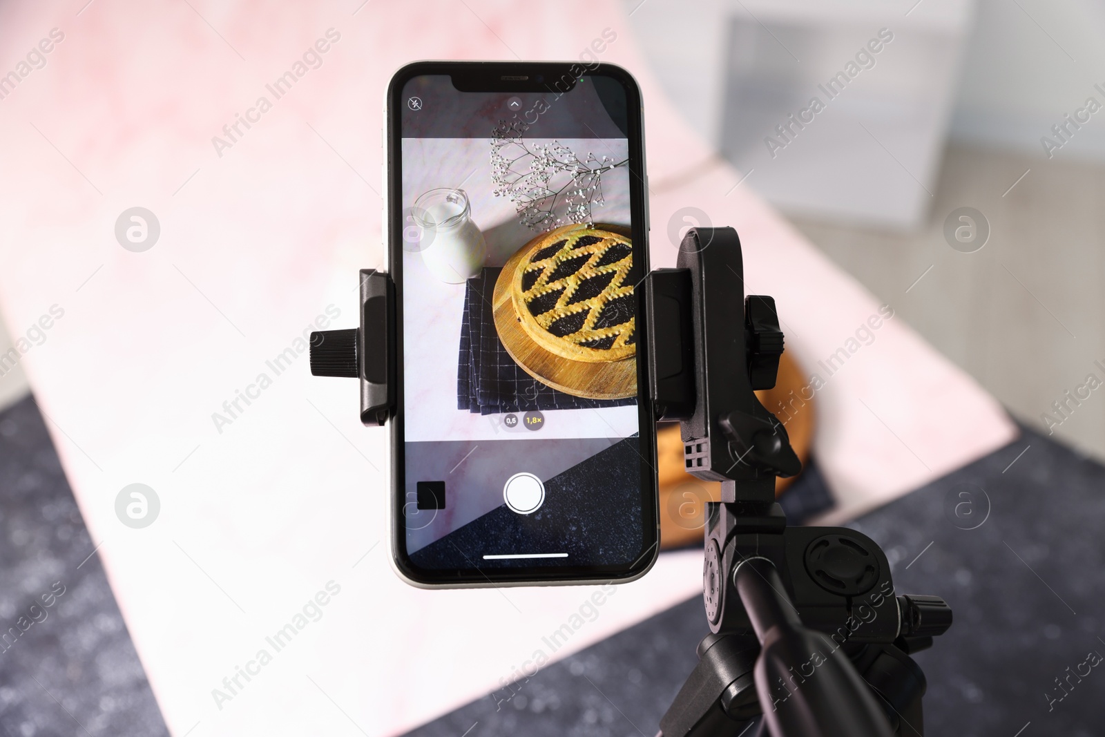 Photo of Shooting tasty pie and milk with smartphone in studio, above view. Professional food photography
