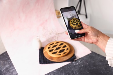 Photo of Woman taking picture of tasty pie and milk in studio, selective focus. Professional food photography