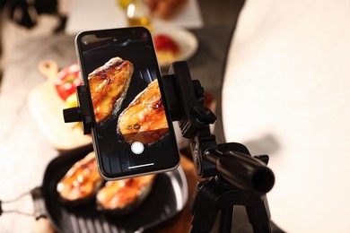 Photo of Shooting tasty roasted fish with smartphone in studio, selective focus. Professional food photography