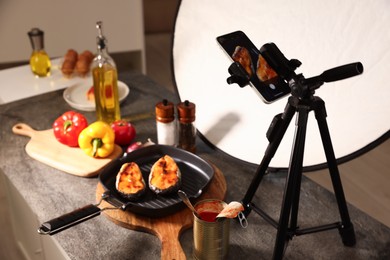 Photo of Shooting tasty roasted fish with smartphone in studio. Professional food photography