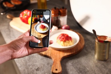 Photo of Woman taking picture of tasty pasta and ingredients in studio, selective focus. Professional food photography