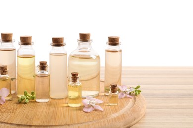 Photo of Bottles of essential oils and different plants on wooden table against white background