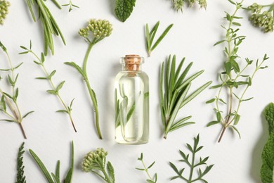 Photo of Essential oil and different plants on white background, flat lay
