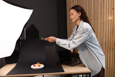 Photo of Woman taking picture of tasty pasta with smartphone in studio. Professional food photography