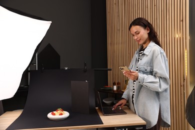 Photo of Woman looking at pictures after shooting in studio. Professional food photography