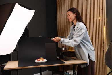 Photo of Woman taking picture of tasty pasta with smartphone in studio. Professional food photography