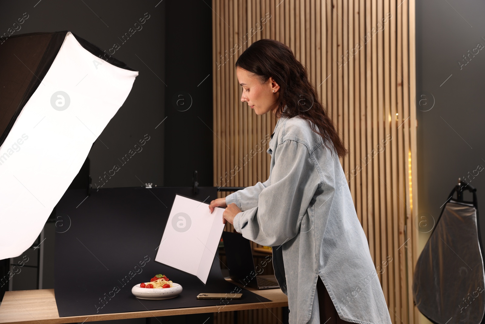 Photo of Woman creating composition with tasty pasta in studio. Professional food photography