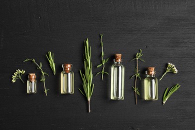 Photo of Essential oils and different plants on black wooden background, flat lay