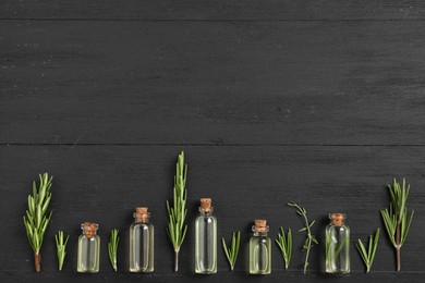 Photo of Essential oils and plants on black wooden background, flat lay. Space for text