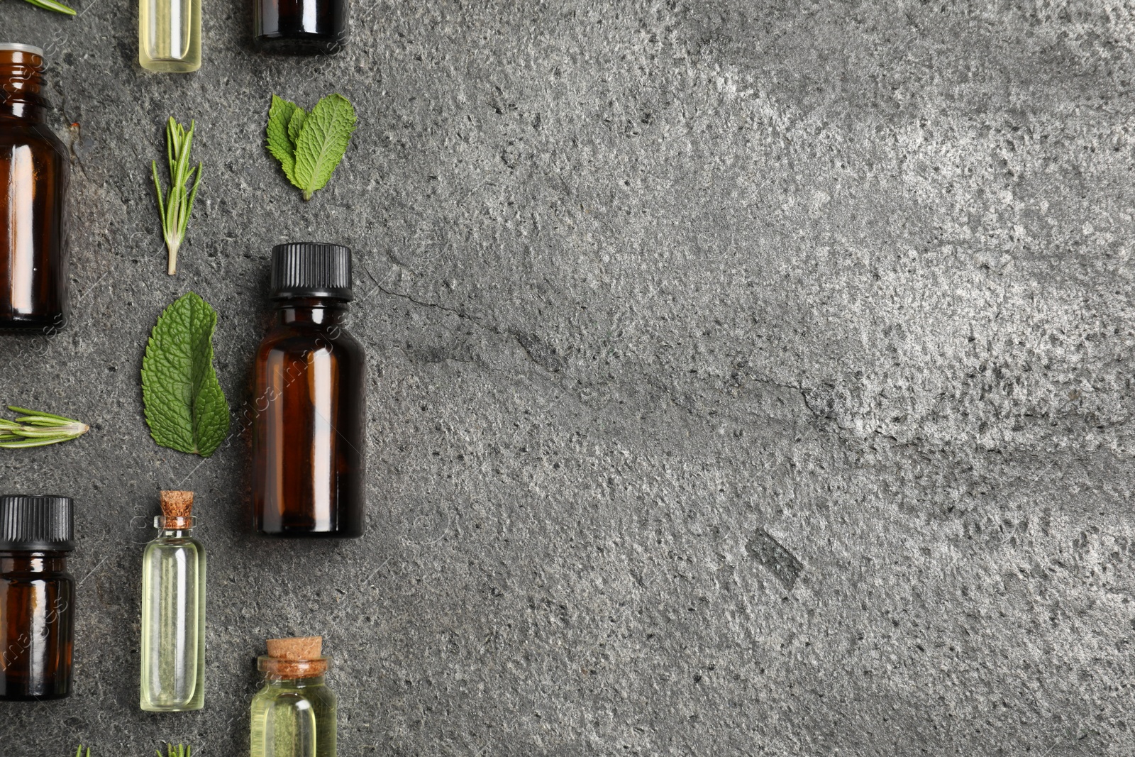 Photo of Essential oils and different plants on grey background, flat lay