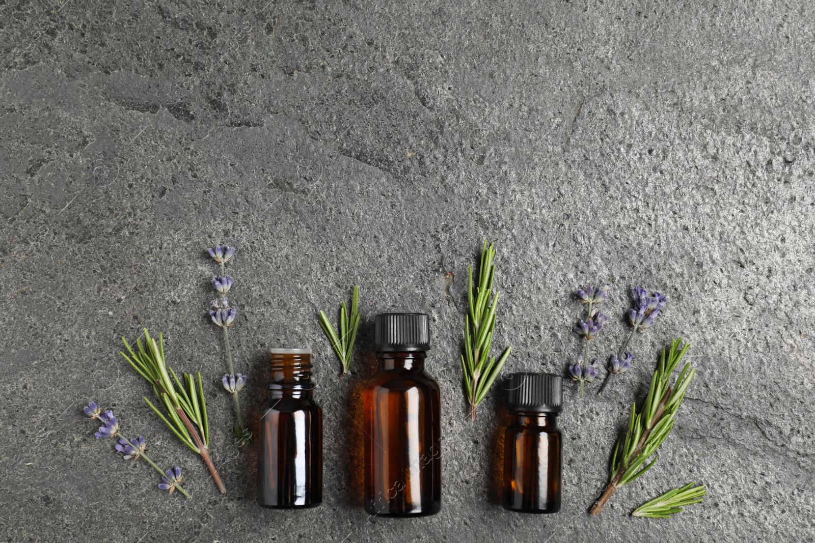 Photo of Essential oils and different plants on grey background, flat lay
