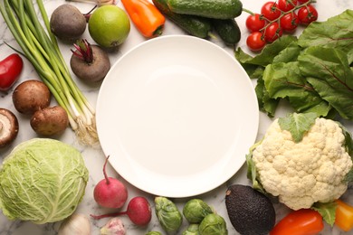 Photo of Healthy vegetarian food. Empty plate surrounded by different products on white marble table, flat lay