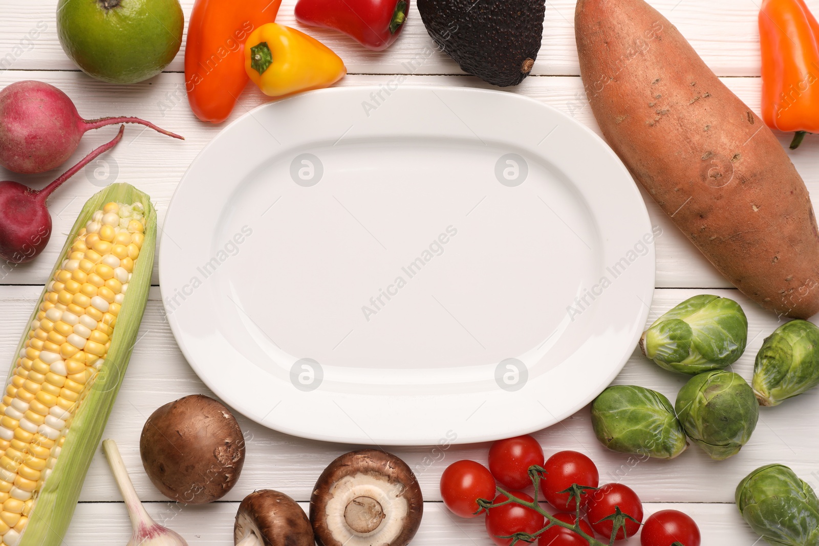 Healthy vegetarian food. Empty plate surrounded by different products on white wooden table, flat lay Photo of Healthy vegetarian food. Empty plate surrounded by different products on white wooden table, flat lay