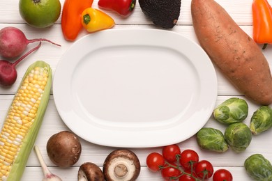 Photo of Healthy vegetarian food. Empty plate surrounded by different products on white wooden table, flat lay