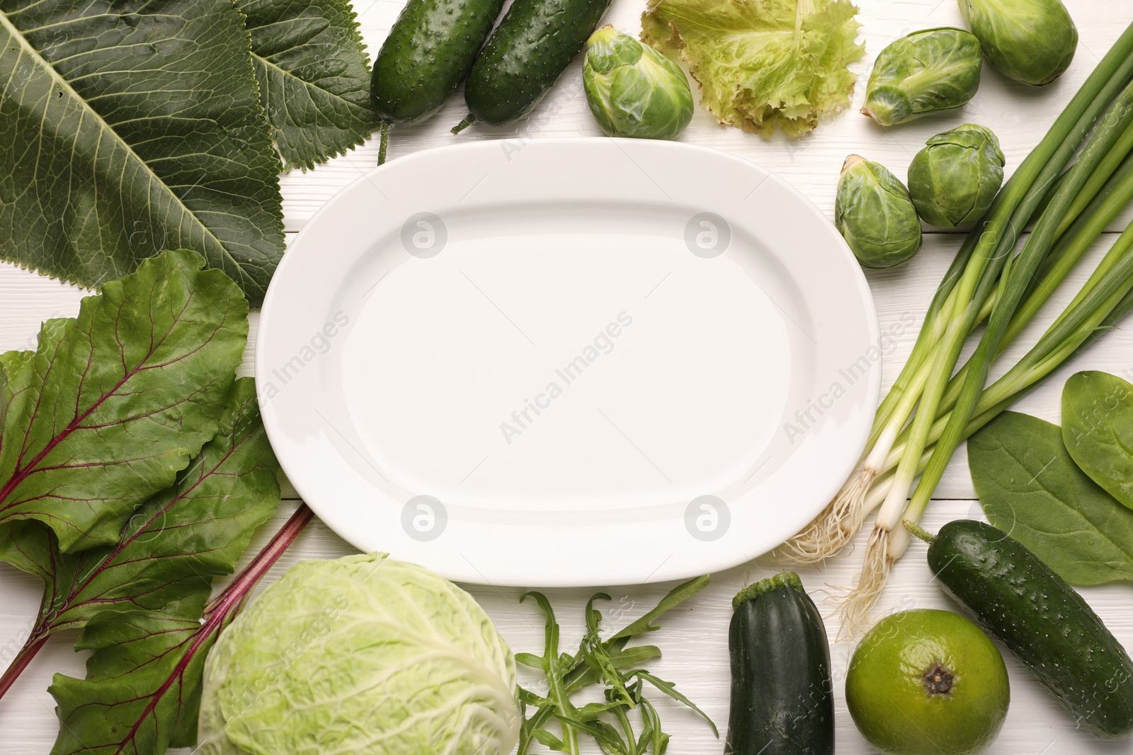 Healthy vegetarian food. Empty plate surrounded by different products on white wooden table, flat lay Photo of Healthy vegetarian food. Empty plate surrounded by different products on white wooden table, flat lay
