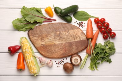 Photo of Healthy vegetarian food. Empty board surrounded by different products and peppercorns on white wooden table, flat lay