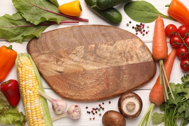 Photo of Healthy vegetarian food. Empty board surrounded by different products and peppercorns on white wooden table, flat lay