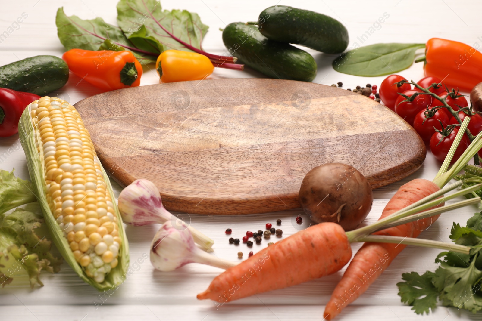 Healthy vegetarian food. Empty board surrounded by different products and peppercorns on white wooden table, closeup Photo of Healthy vegetarian food. Empty board surrounded by different products and peppercorns on white wooden table, closeup