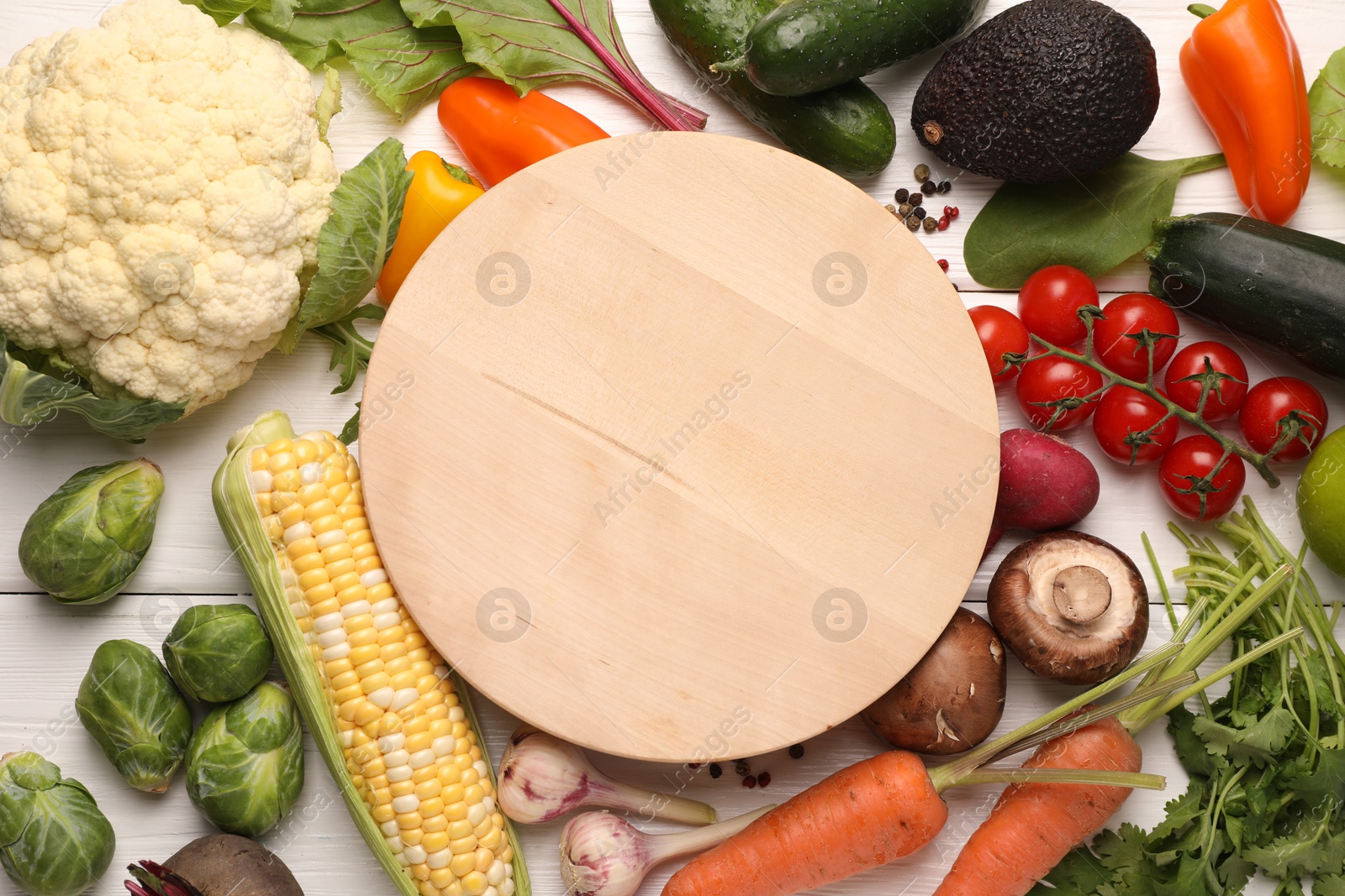 Healthy vegetarian food. Empty board surrounded by different products on white wooden table, flat lay Photo of Healthy vegetarian food. Empty board surrounded by different products on white wooden table, flat lay