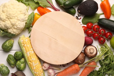 Photo of Healthy vegetarian food. Empty board surrounded by different products on white wooden table, flat lay