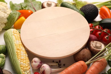 Photo of Healthy vegetarian food. Empty board surrounded by different products on white wooden table, closeup