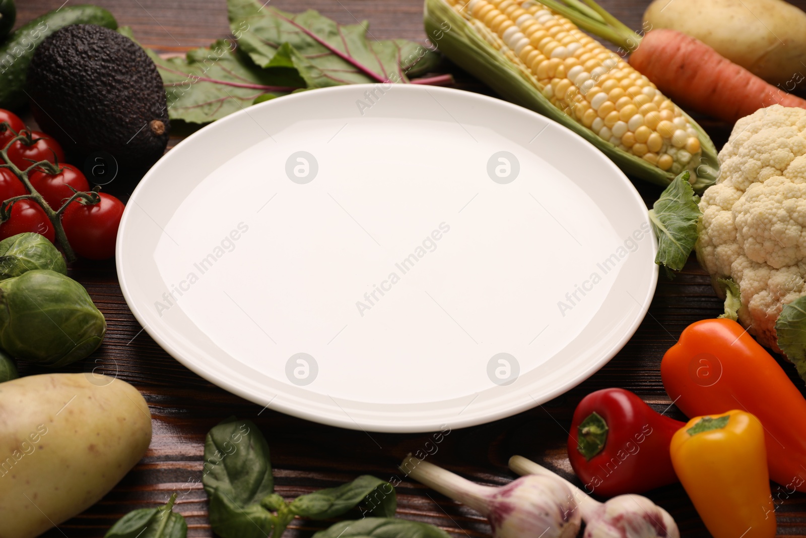 Healthy vegetarian food. Empty plate surrounded by different products on wooden table, closeup Photo of Healthy vegetarian food. Empty plate surrounded by different products on wooden table, closeup