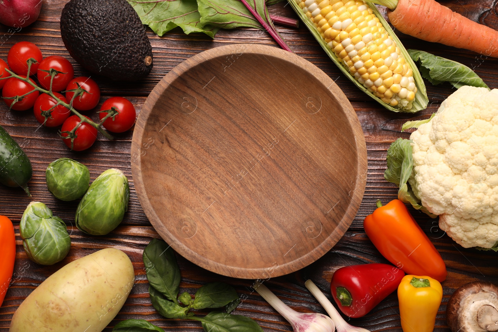 Healthy vegetarian food. Empty plate surrounded by different products on wooden table, flat lay Photo of Healthy vegetarian food. Empty plate surrounded by different products on wooden table, flat lay