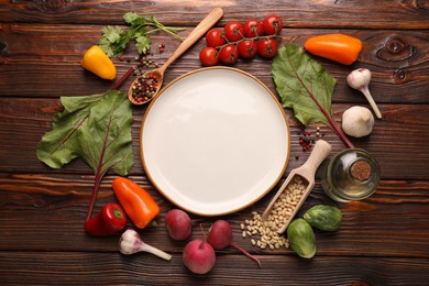 Photo of Healthy vegetarian food. Empty plate surrounded by different products on wooden table, flat lay