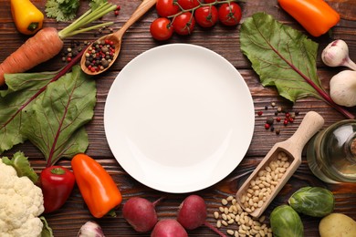 Photo of Healthy vegetarian food. Empty plate surrounded by different products on wooden table, flat lay