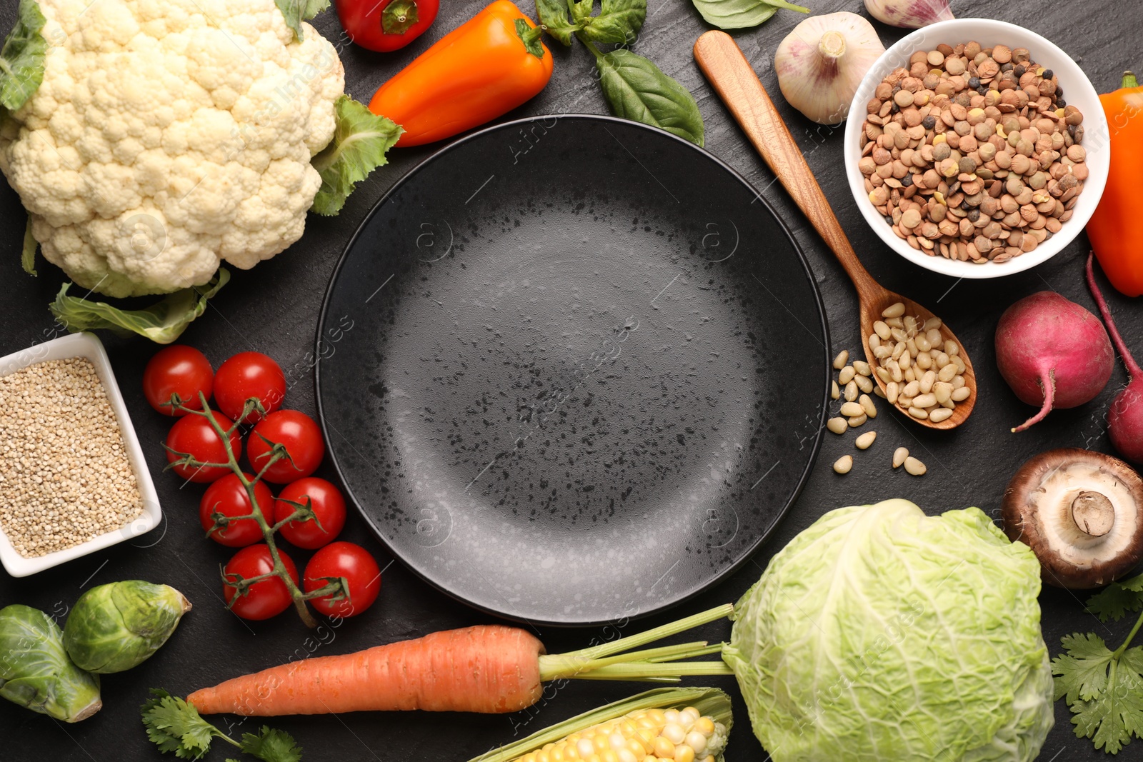 Healthy vegetarian food. Empty plate surrounded by different products on dark textured table, flat lay Photo of Healthy vegetarian food. Empty plate surrounded by different products on dark textured table, flat lay