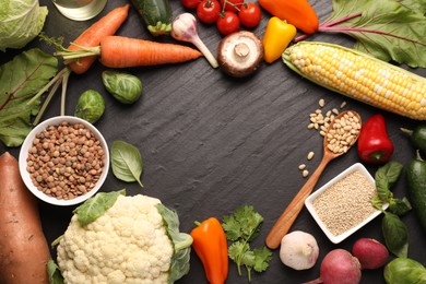 Photo of Healthy vegetarian food. Frame of different products on dark textured table, flat lay. Space for text