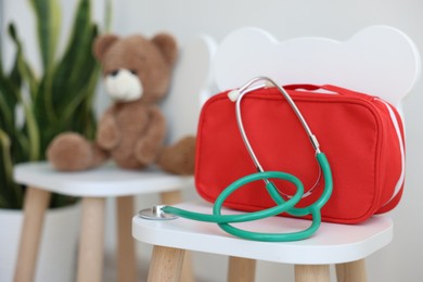 Photo of Pediatrician concept. Toy bear, medical bag and stethoscope on chairs in clinic, selective focus