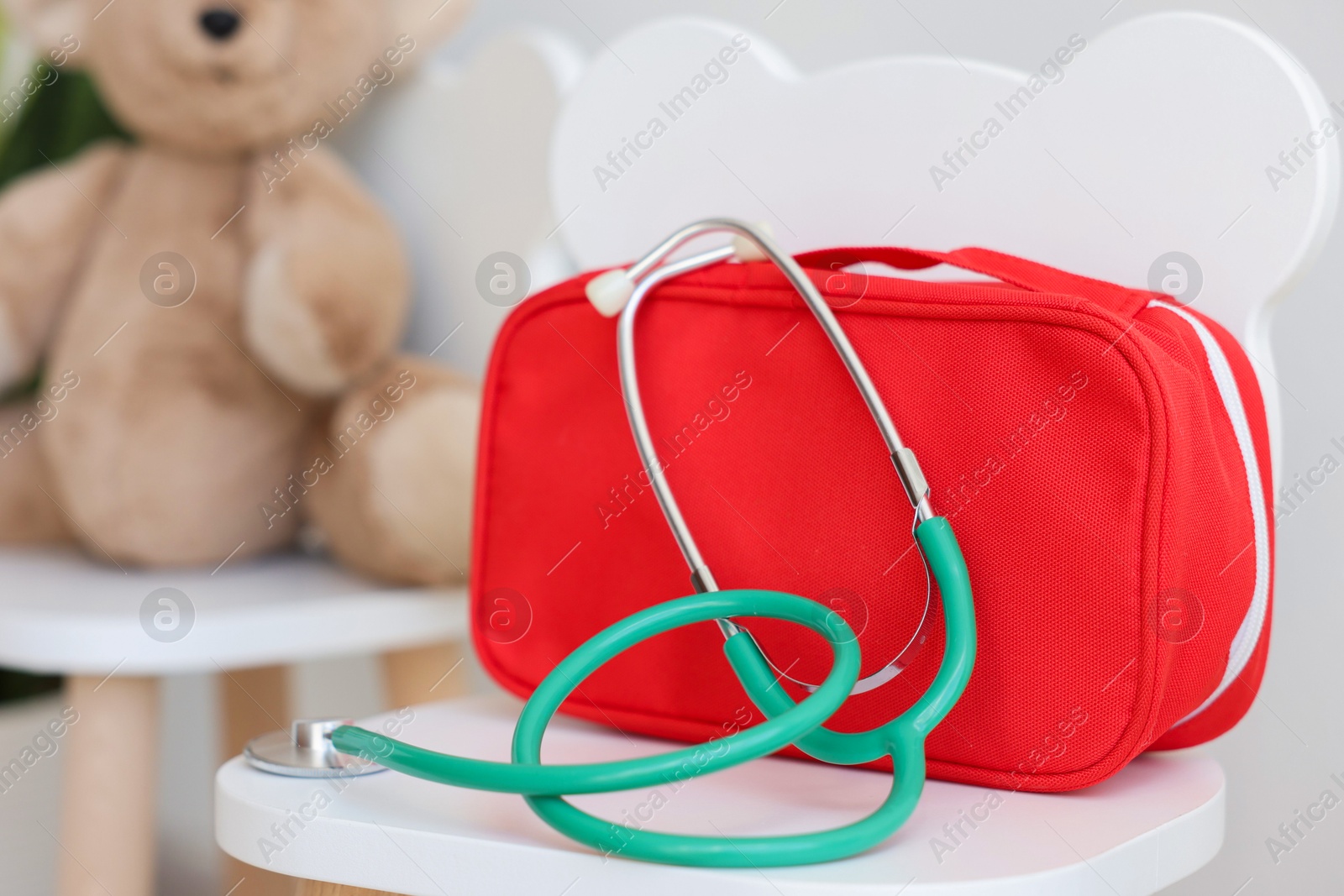 Photo of Pediatrician concept. Toy bear, medical bag and stethoscope on chairs in clinic, selective focus