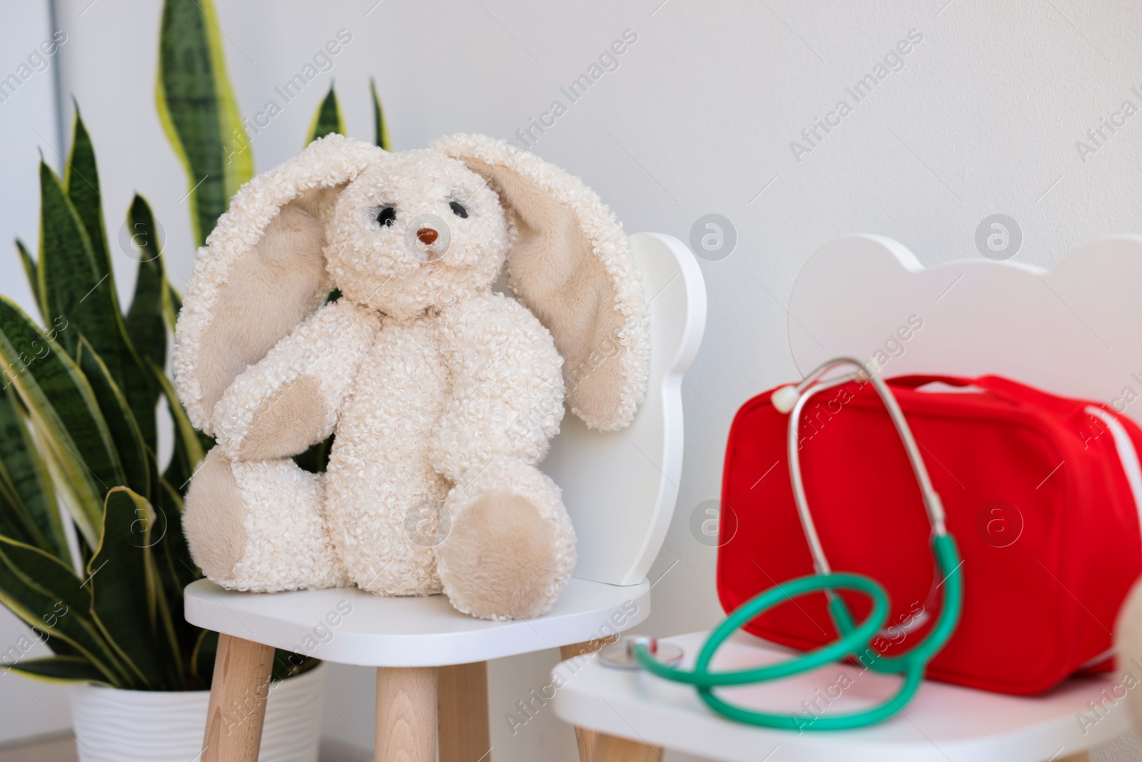 Photo of Pediatrician concept. Toy bunny, medical bag and stethoscope on chairs in clinic