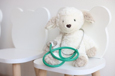 Photo of Pediatrician concept. Toy sheep and stethoscope on chair in clinic