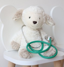 Photo of Pediatrician concept. Toy sheep and stethoscope on chair in clinic