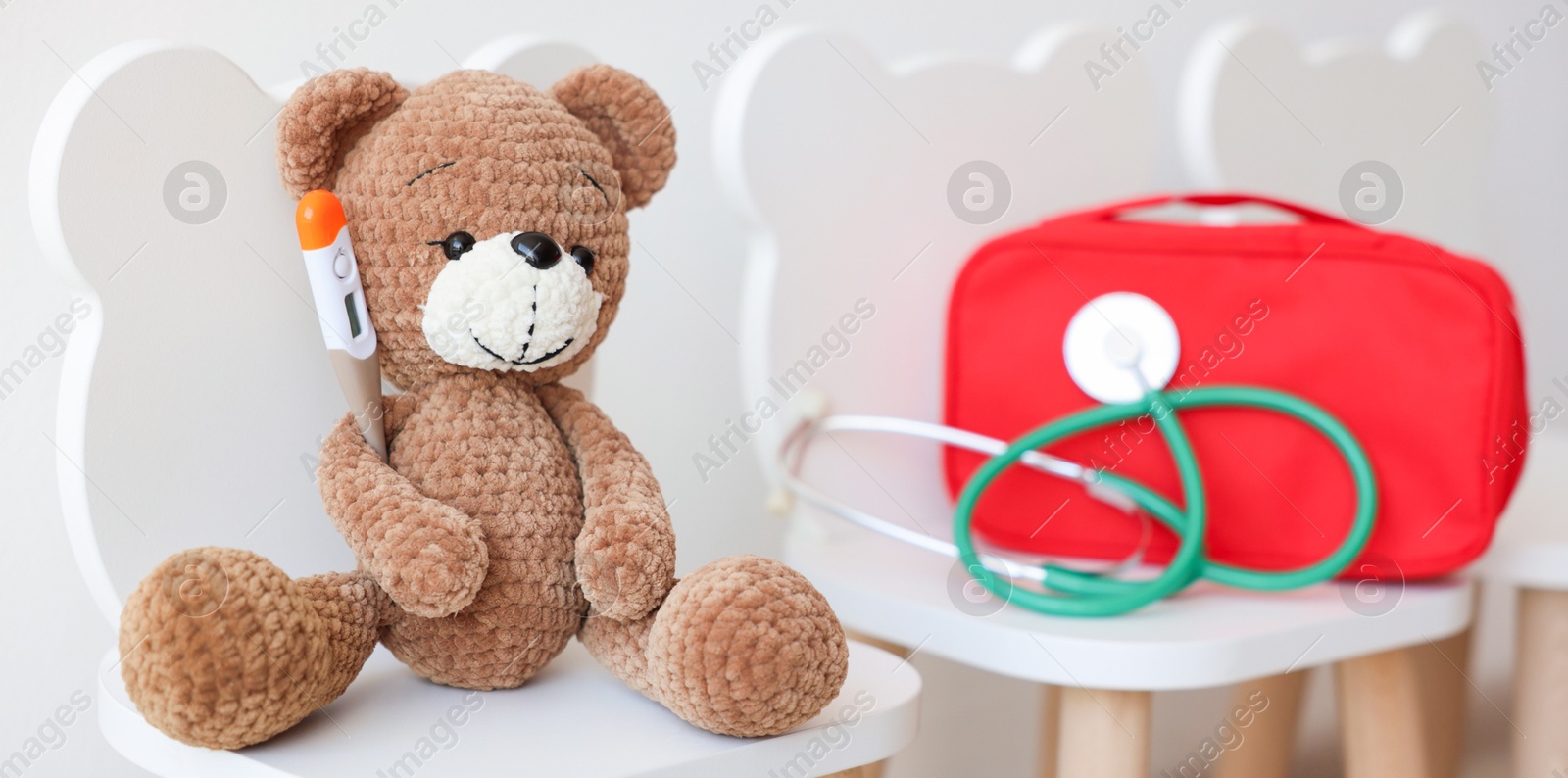 Photo of Pediatrician concept. Toy bear, thermometer, medical bag and stethoscope on chairs in clinic