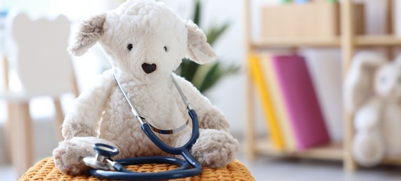 Photo of Pediatrician concept. Toy sheep and stethoscope on pouf in clinic, closeup. Space for text