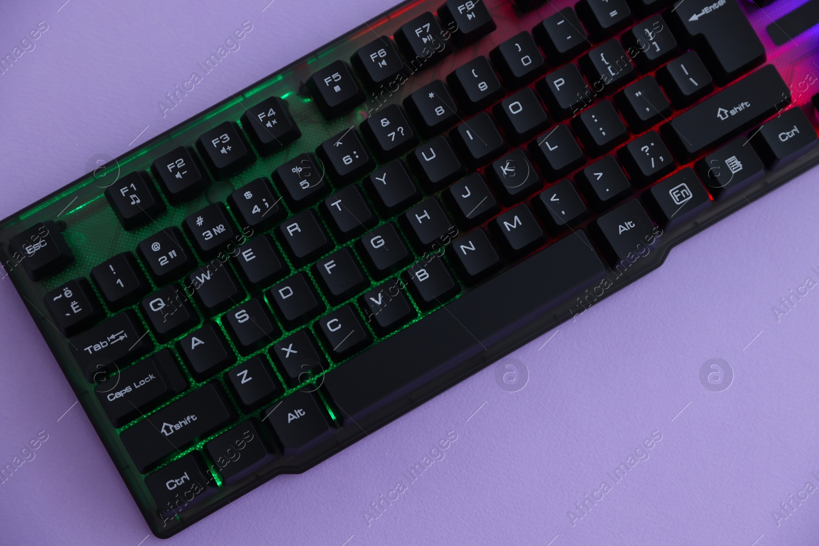 Modern computer keyboard with RGB lighting on violet background, top view Photo of Modern computer keyboard with RGB lighting on violet background, top view