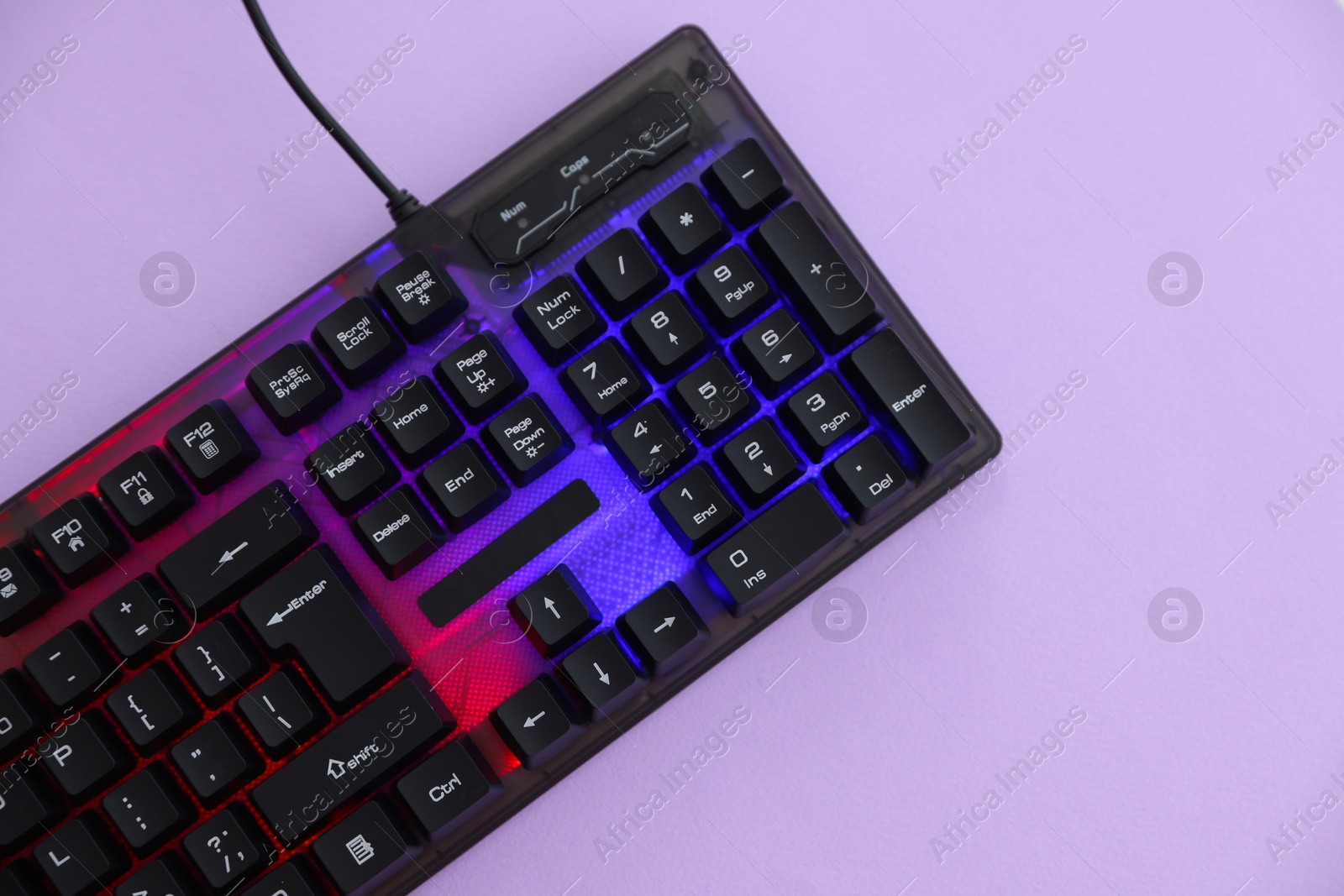 Modern computer keyboard with RGB lighting on violet background, top view. Space for text Photo of Modern computer keyboard with RGB lighting on violet background, top view. Space for text