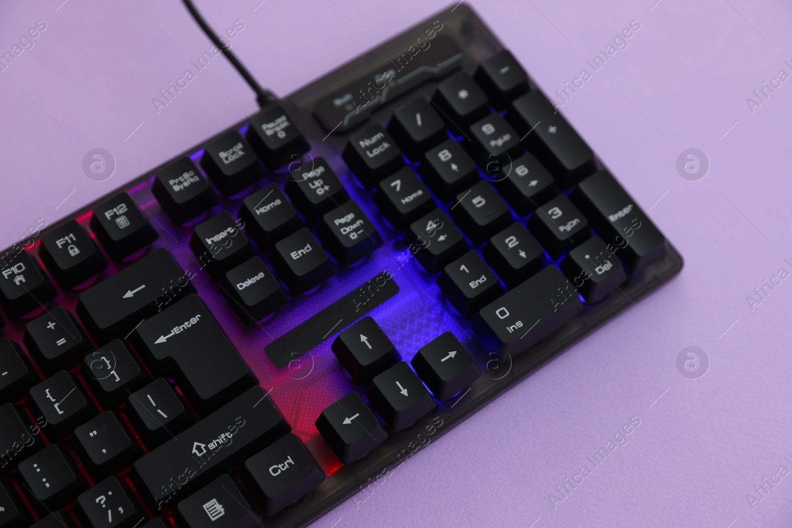 Modern computer keyboard with RGB lighting on violet background, above view Photo of Modern computer keyboard with RGB lighting on violet background, above view