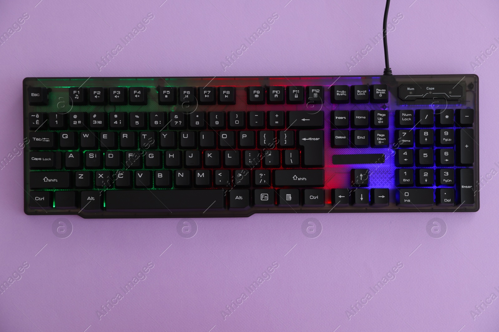 Photo of Modern computer keyboard with RGB lighting on violet background, top view