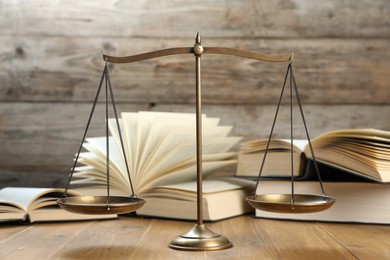Photo of Scales of justice and books on wooden table