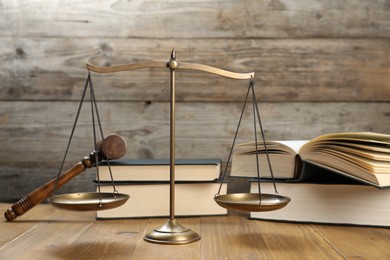 Photo of Scales of justice, gavel and books on wooden table